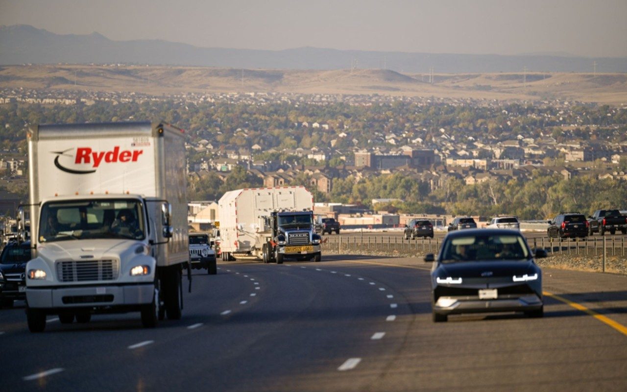 a truck carrying the GPS III SV07 satellite driving on Colorado’s C-470 highway​